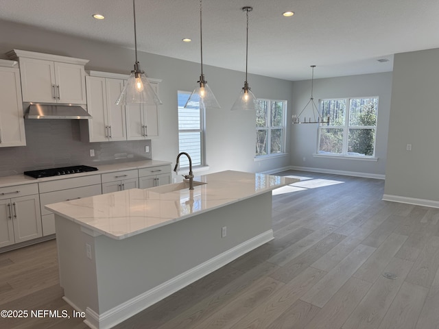 kitchen with black gas stovetop, pendant lighting, sink, and a center island with sink