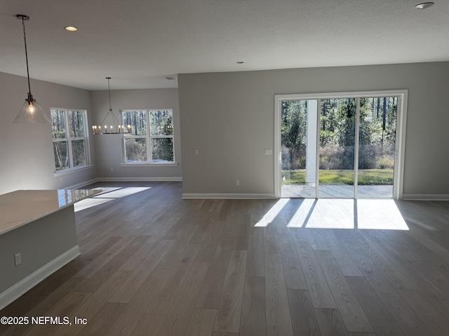 unfurnished living room with dark hardwood / wood-style flooring, a notable chandelier, and a textured ceiling