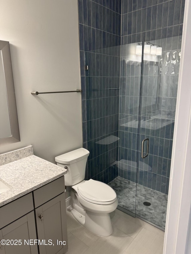 bathroom featuring vanity, toilet, and a shower with shower door