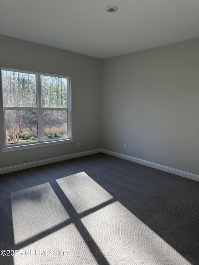 spare room featuring dark carpet