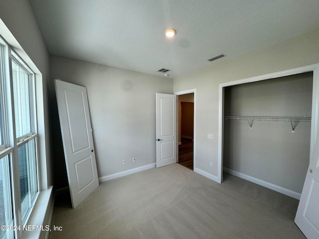 unfurnished bedroom with a closet, light carpet, and a textured ceiling