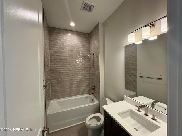 full bathroom featuring hardwood / wood-style flooring, tiled shower / bath, vanity, and toilet