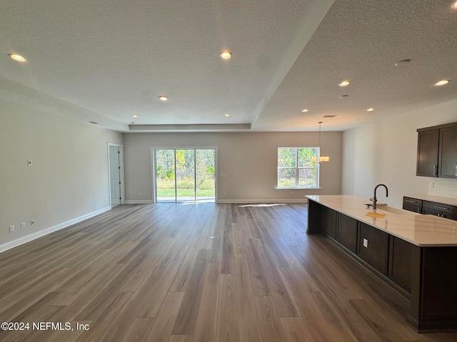 kitchen with hardwood / wood-style floors, dark brown cabinets, light stone countertops, and a textured ceiling