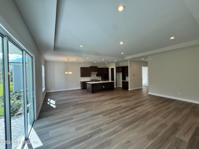 unfurnished living room featuring hardwood / wood-style flooring, a textured ceiling, and an inviting chandelier