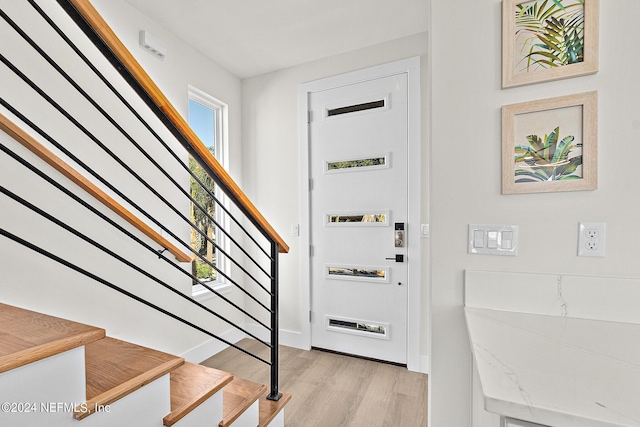 foyer entrance featuring stairway, baseboards, and light wood-style flooring