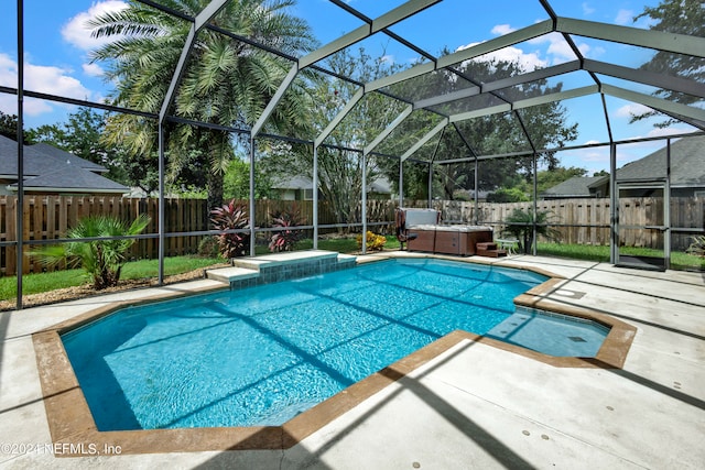 view of swimming pool with a hot tub, a patio, and a lanai