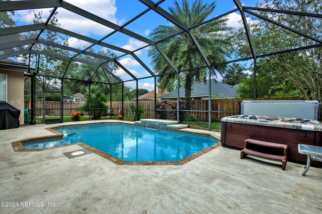 view of swimming pool featuring a grill, a lanai, a patio area, and a hot tub