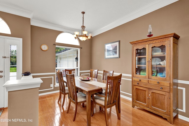 dining space with a healthy amount of sunlight, an inviting chandelier, crown molding, and light hardwood / wood-style flooring