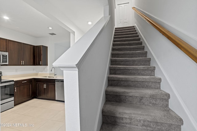 stairway featuring tile patterned floors and sink