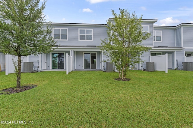 rear view of house featuring central AC unit and a yard