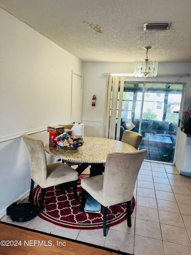 tiled dining area featuring a textured ceiling and a notable chandelier