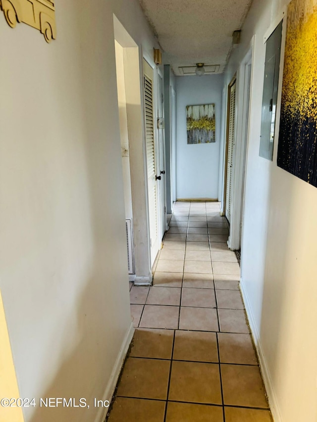 hall featuring electric panel and light tile patterned floors