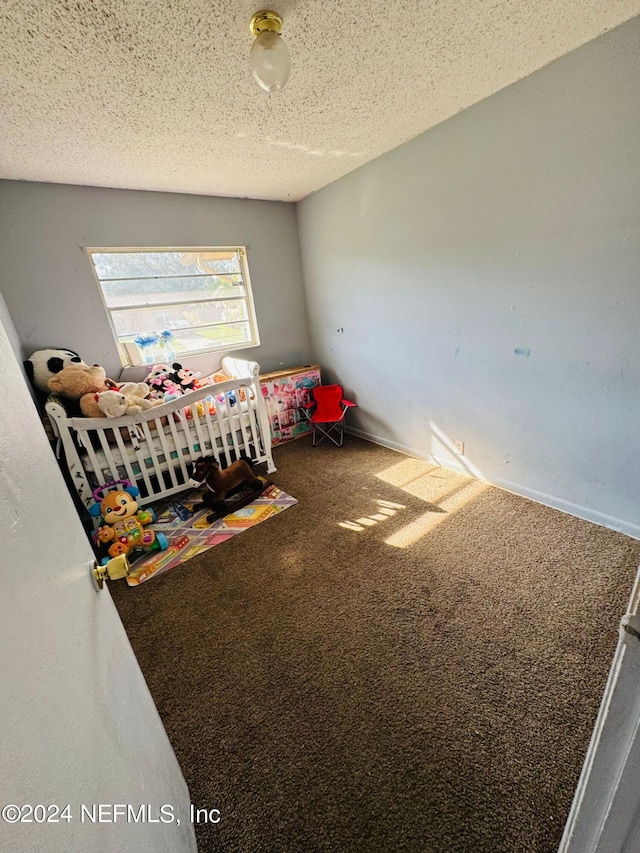 carpeted bedroom featuring a textured ceiling and a crib