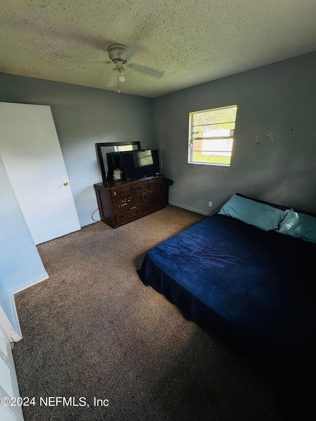 carpeted bedroom featuring ceiling fan and a textured ceiling