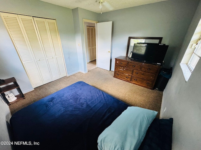 bedroom featuring a textured ceiling, light colored carpet, and a closet