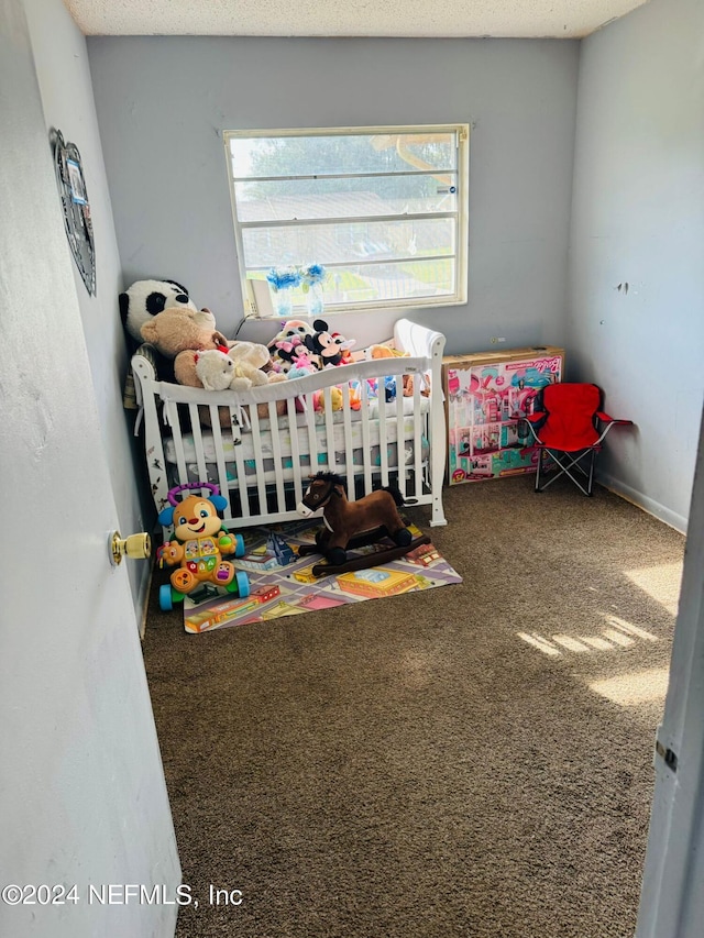 carpeted bedroom featuring a textured ceiling and a nursery area