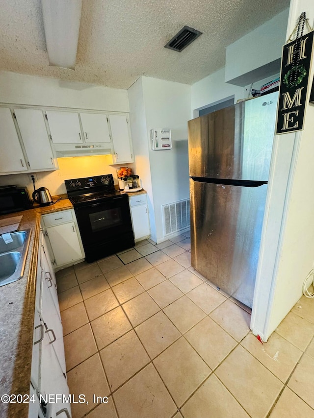 kitchen with stainless steel fridge, black range with electric cooktop, light tile patterned floors, and white cabinetry