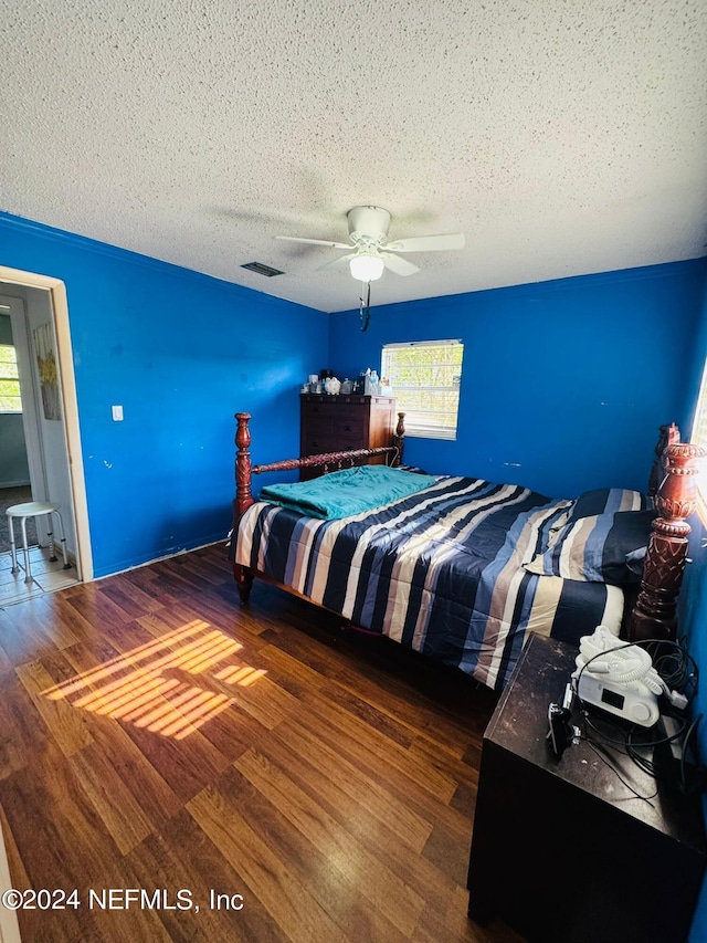 bedroom with a textured ceiling, dark hardwood / wood-style flooring, and ceiling fan