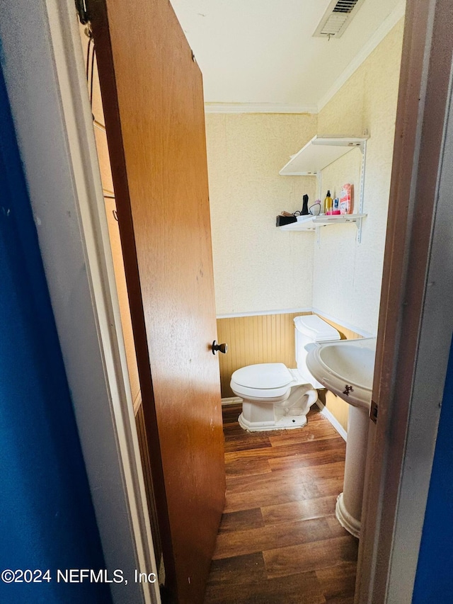 bathroom with crown molding, toilet, and hardwood / wood-style flooring