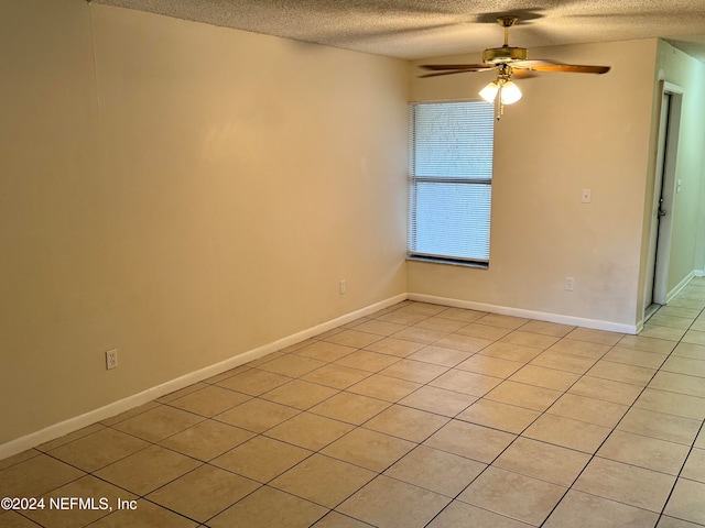 empty room with a textured ceiling, light tile patterned floors, and ceiling fan