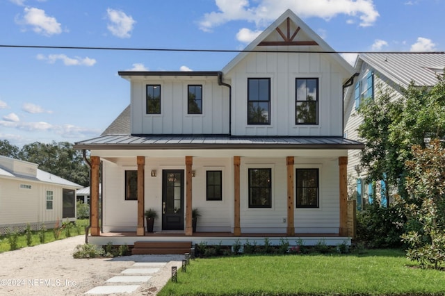 modern farmhouse style home featuring board and batten siding, covered porch, a front lawn, and a standing seam roof