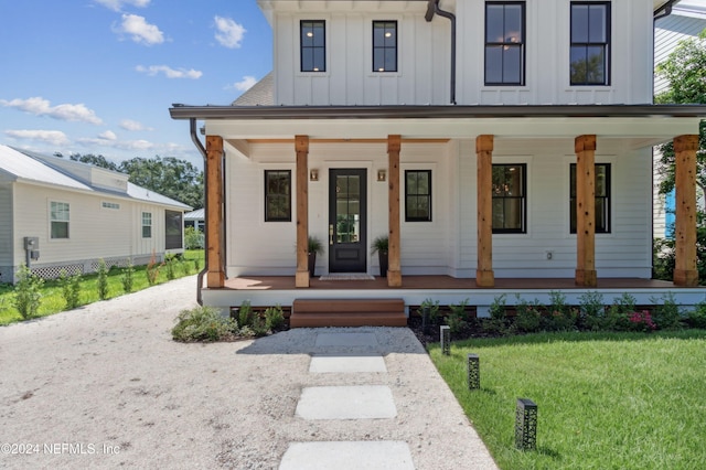 modern inspired farmhouse featuring covered porch and a front yard