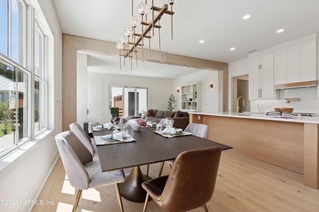 dining area with light hardwood / wood-style floors, an inviting chandelier, and sink