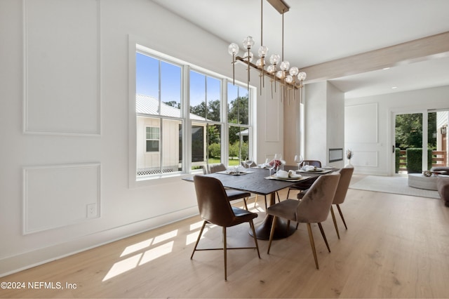 dining room with a healthy amount of sunlight, light wood-type flooring, and an inviting chandelier