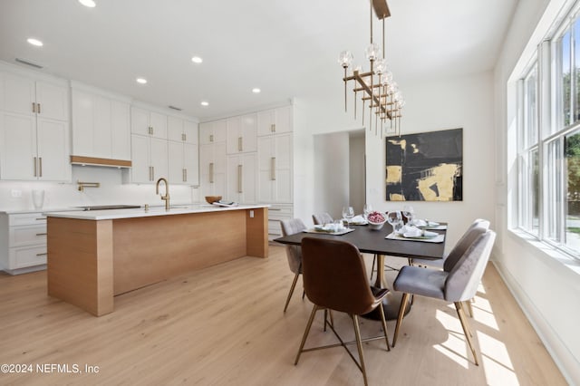 dining area with recessed lighting, light wood-style flooring, and an inviting chandelier