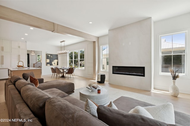 living room with an inviting chandelier, plenty of natural light, and light wood-type flooring