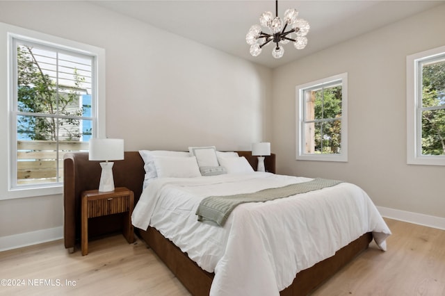 bedroom featuring light wood-style floors, baseboards, and a notable chandelier