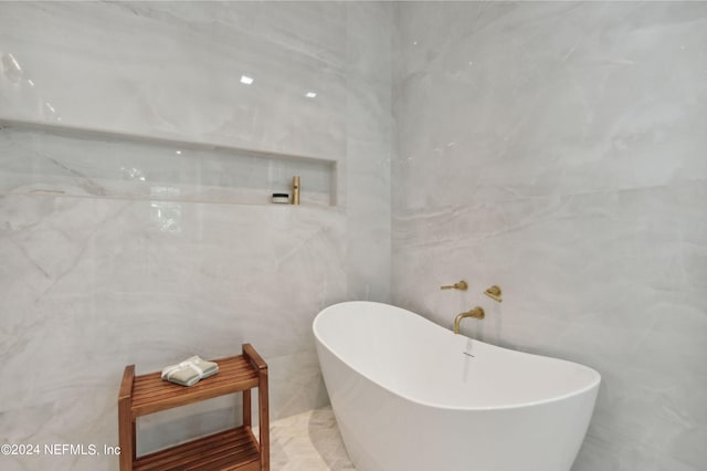 bathroom featuring a tub to relax in and tile walls