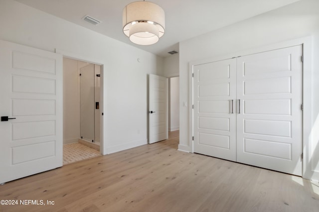 unfurnished bedroom featuring a closet, wood finished floors, visible vents, and baseboards