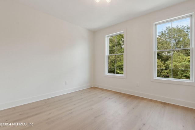 spare room with light wood-style floors, plenty of natural light, and baseboards