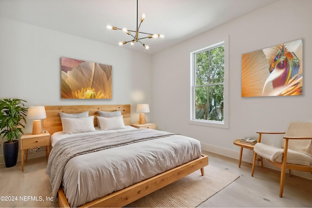 bedroom with baseboards, light wood-style flooring, and an inviting chandelier