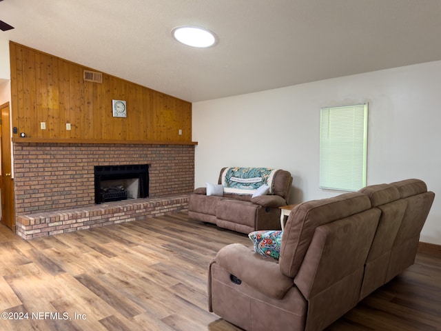 living room with a fireplace, vaulted ceiling, dark hardwood / wood-style flooring, and wood walls