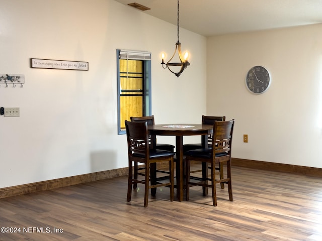 dining area with wood-type flooring and a notable chandelier