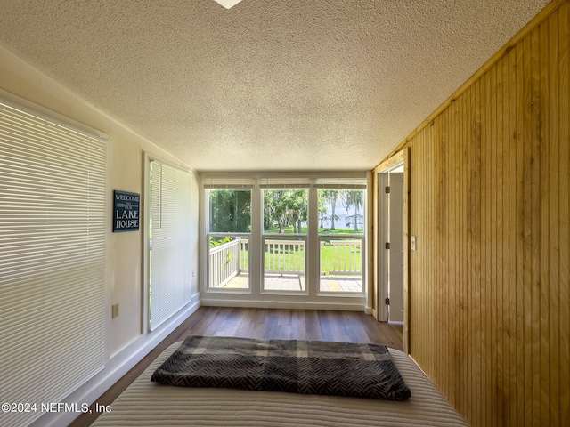 doorway to outside with a textured ceiling, hardwood / wood-style flooring, and wood walls