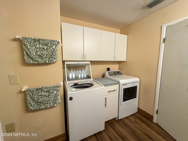 laundry area featuring dark hardwood / wood-style floors, washing machine and dryer, cabinets, and a textured ceiling