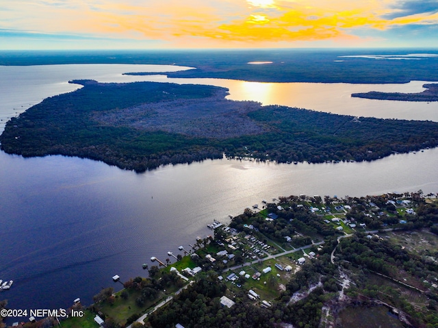 aerial view at dusk featuring a water view