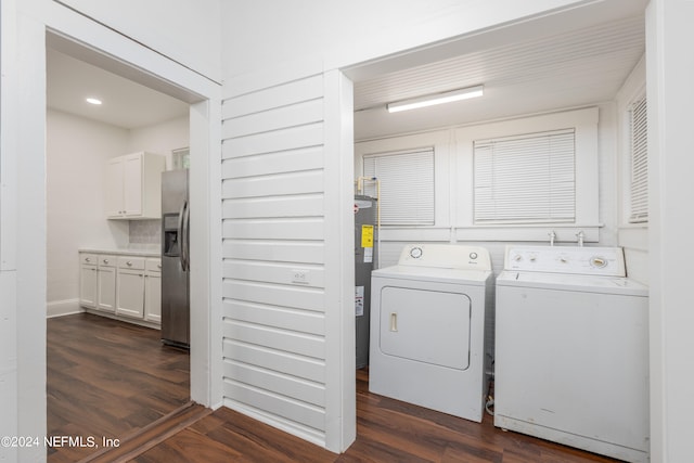 laundry area featuring electric water heater, independent washer and dryer, and dark hardwood / wood-style flooring