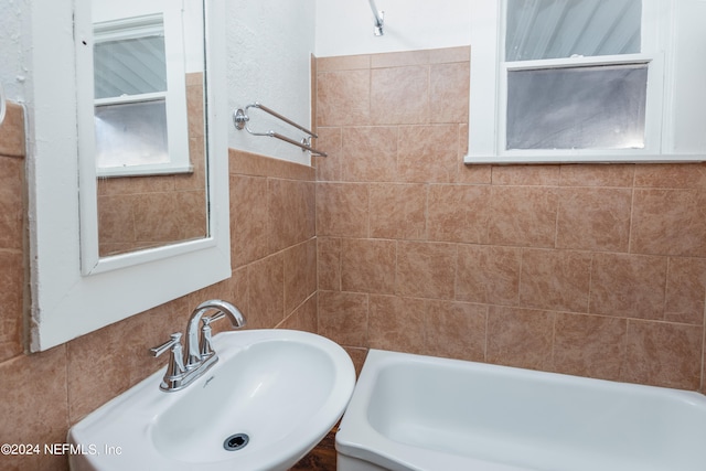 bathroom with a tub to relax in and sink