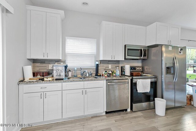 kitchen featuring light stone counters, stainless steel appliances, and white cabinetry