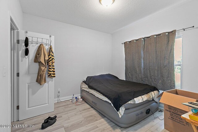 bedroom with a textured ceiling and light hardwood / wood-style floors