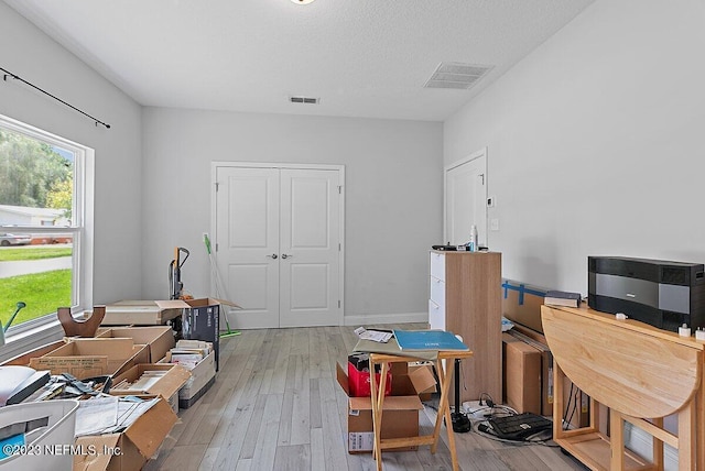 office area with light wood-type flooring and a textured ceiling