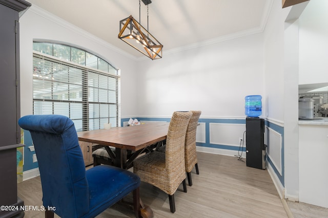 dining space featuring light hardwood / wood-style floors, crown molding, and a chandelier