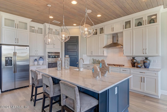 kitchen featuring wood ceiling, hanging light fixtures, appliances with stainless steel finishes, a center island with sink, and wall chimney range hood