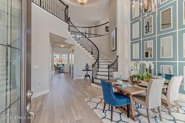 dining area with wood-type flooring, a high ceiling, and a notable chandelier