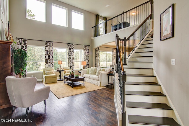 living room featuring a towering ceiling, plenty of natural light, and dark hardwood / wood-style floors