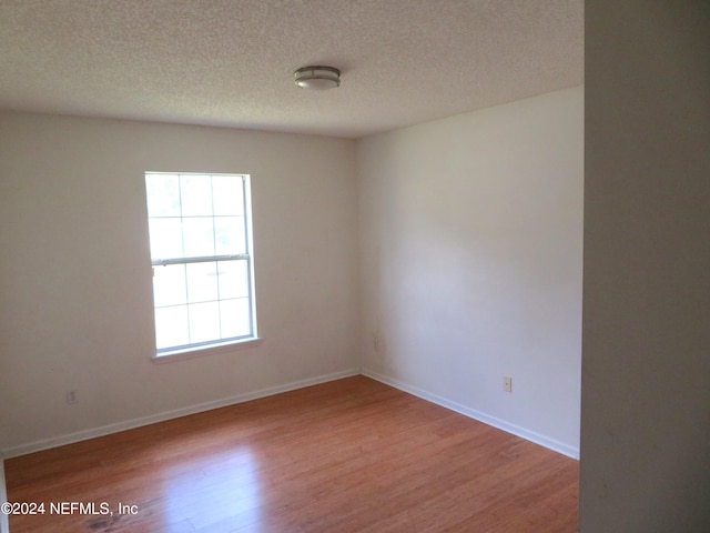 unfurnished room with wood-type flooring and a textured ceiling